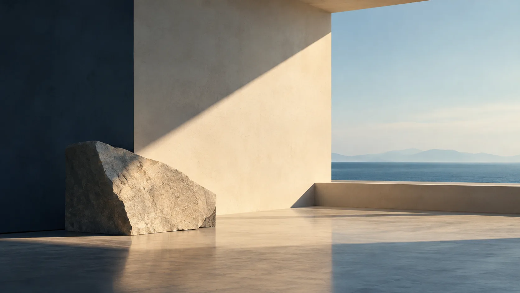 Rough boulder in a sunlit concrete room that opens onto a calm blue sea