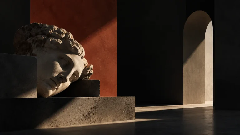 Classical marble head resting on its side on a stone plinth in a dark gallery